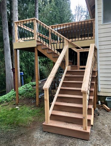 Wooden outdoor staircase with black metal railings leading to a deck in Battle Ground, WA