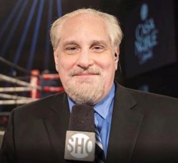 A man in a suit holding a Showtime microphone at a boxing ring.