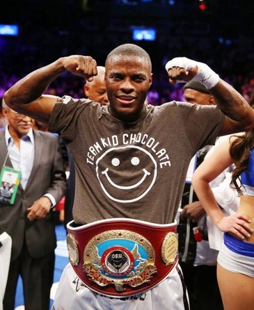 Boxer proudly showing championship belt and flexing muscles in the ring.