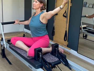 Woman stretching on Pilates reformer.