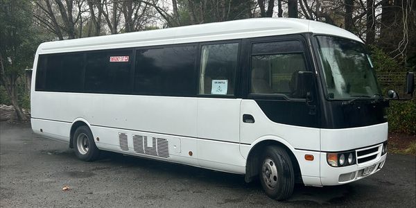 White passenger mini bus parked outdoors with tinted windows.