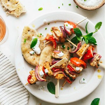 A plate with tofu and vegetable skewers on flatbread