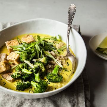 a bowl of broccoli and tofu in a yellow coconut broth with spoon