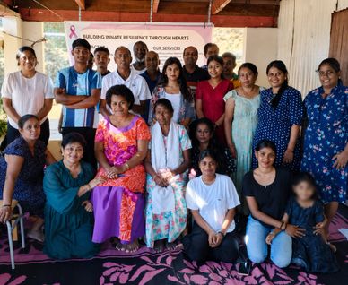 Group of diverse women and men posing together indoors for a community event.