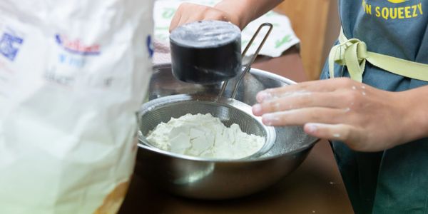 little cook measuring out flour for a recipe