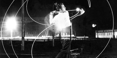 Black and white photo of a man swinging a golf club with light trails around him.