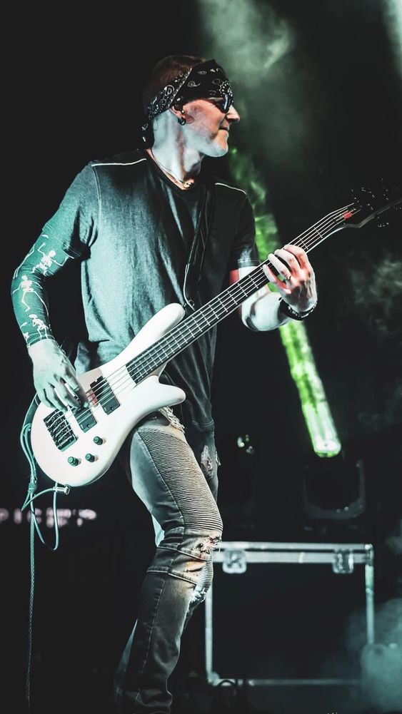 Musician playing bass guitar on stage with dramatic lighting and smoke effects. Spector bass guitar.