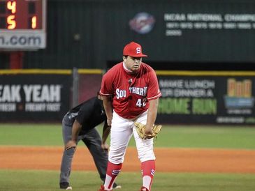 Baseball pitcher in red uniform preparing to pitch on the mound.