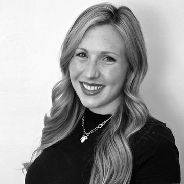 Smiling blonde woman with long hair in black and white photo.