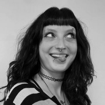 Young woman smiling playfully with tongue out and piercings.