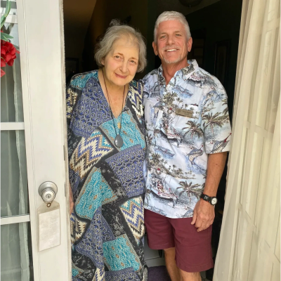 An elderly woman and a middle-aged man smiling at a doorway.