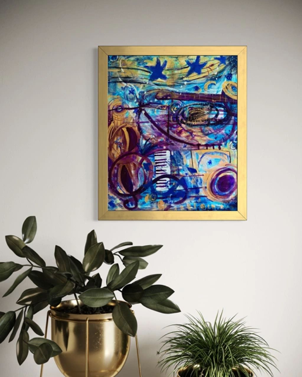 Colorful abstract painting framed in gold above plants.