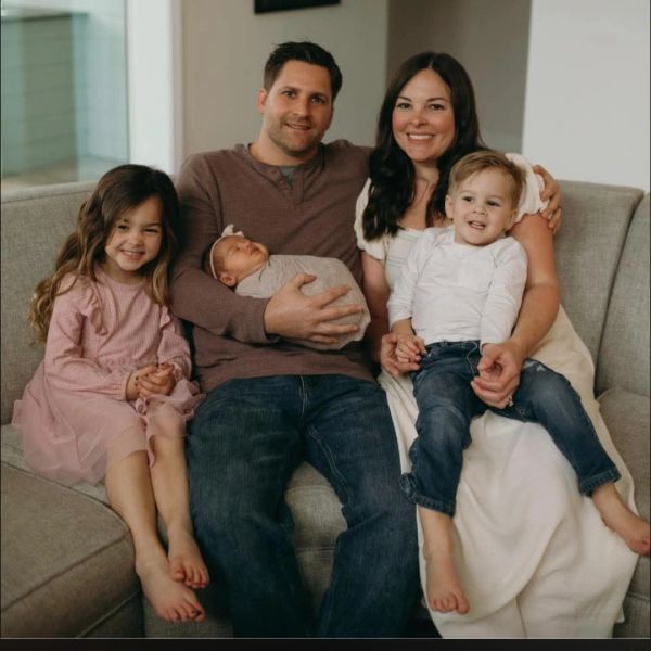 Happy family sitting on a couch with their three children.