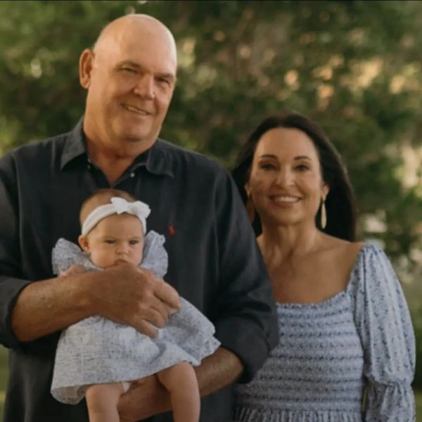 A man holding a baby with a woman standing beside them outdoors.
