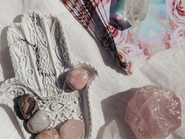 Decorative hand-shaped plate with crystals and tarot cards on fabric.