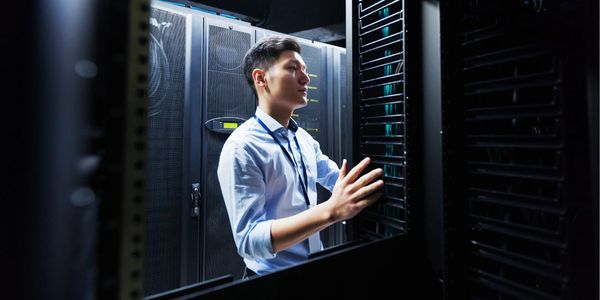 IT professional working inside a server room with racks of servers.