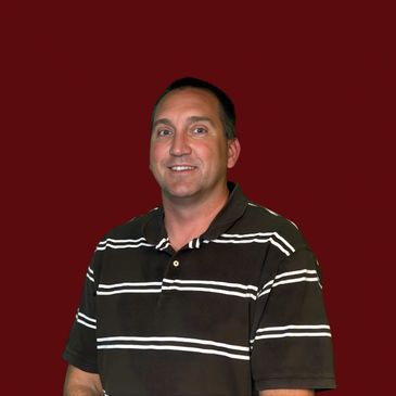 Smiling man in a striped polo shirt against a maroon background.