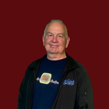 Elderly man smiling against a solid maroon background.
