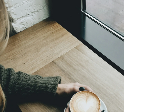 Top view of female holding cup of cappuccino at desk