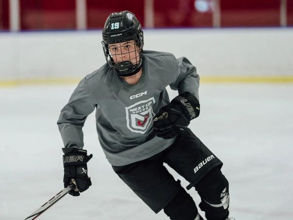 Ice hockey player skating on the rink in full gear.