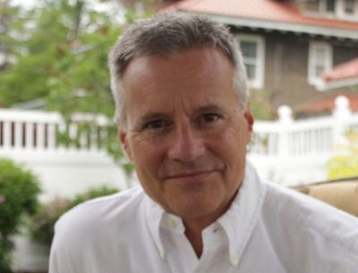 Smiling middle-aged man in white shirt outdoors.