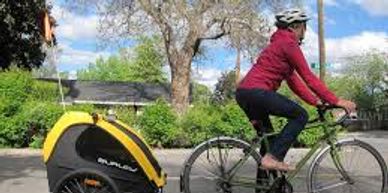 Person cycling with a yellow child trailer attached.