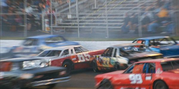 Stock cars racing on a track with intense action.