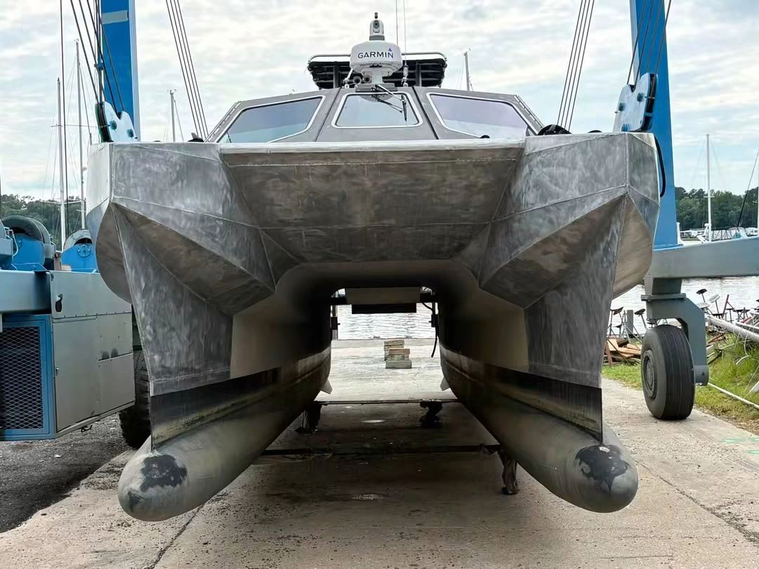 Front view of a metallic catamaran on land.