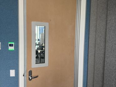 Closed wooden door with a window in an indoor office setting.