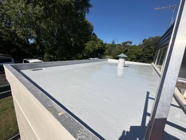 Flat rooftop with a white coating and a vent pipe.