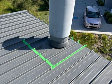 Metal roof with pipe sealed by green tape.