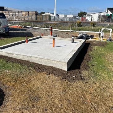 Freshly poured concrete slab with plumbing pipes sticking out.