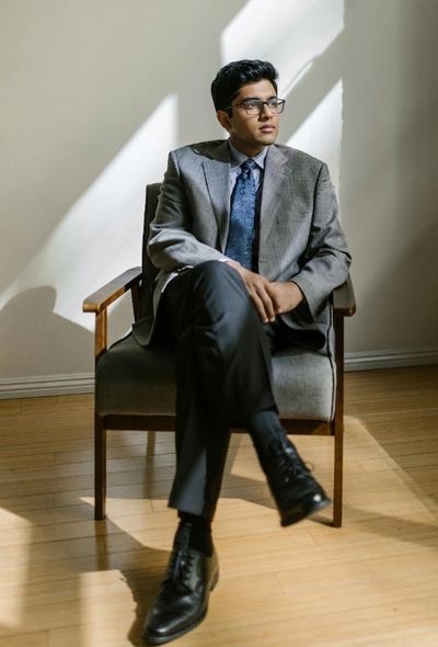 Young man in a suit sitting thoughtfully in a chair with natural light.