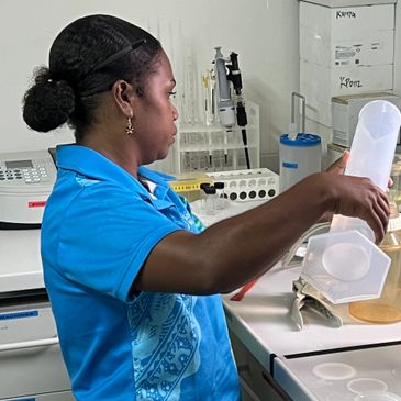 A woman in a blue shirt working with lab equipment in a laboratory.