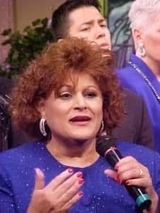 Woman singing passionately into a microphone during a performance.