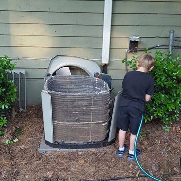 Company owner's son helping maintain an air conditioner in Woodstock, ga.
