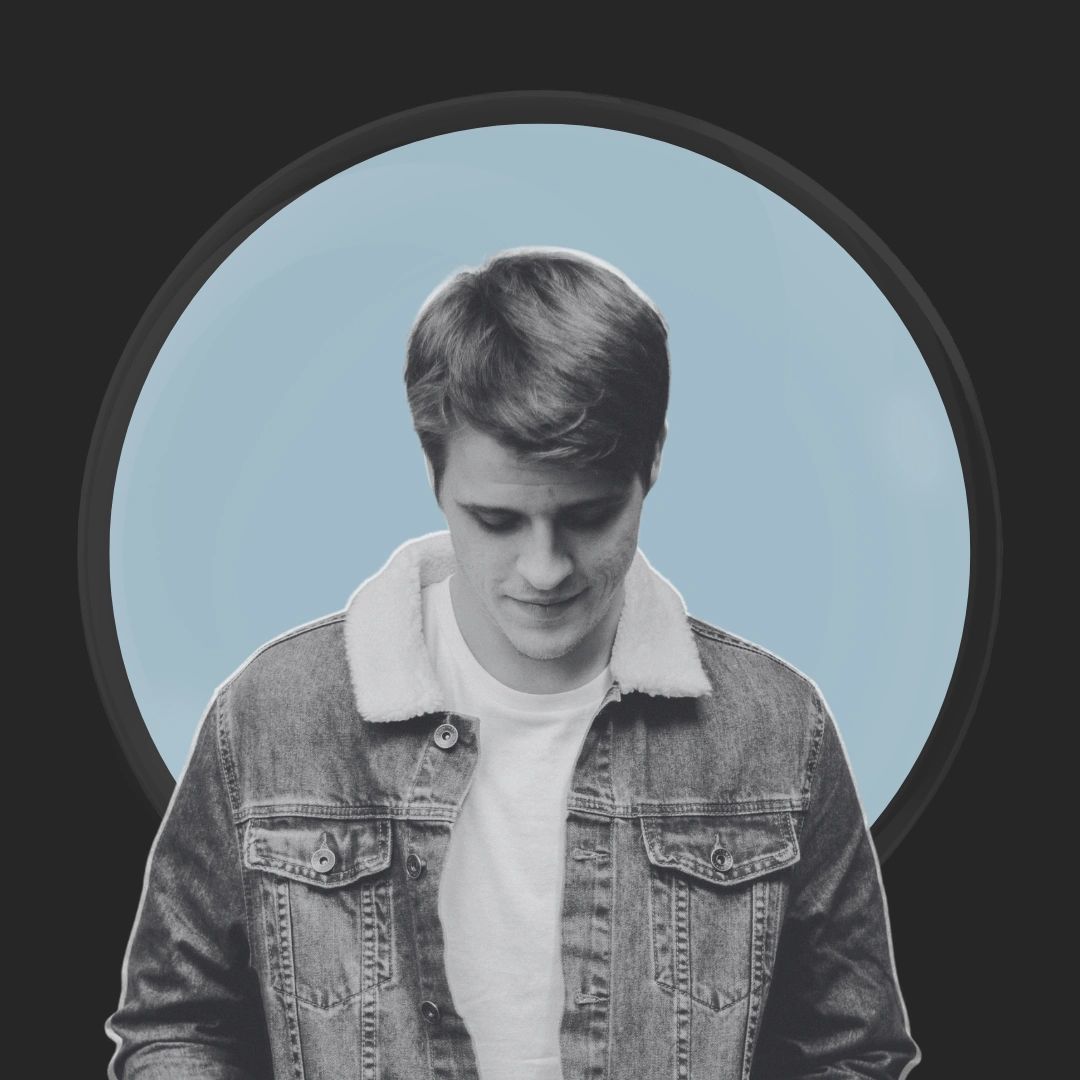 Young man in a denim jacket looking down with a blue circular background.