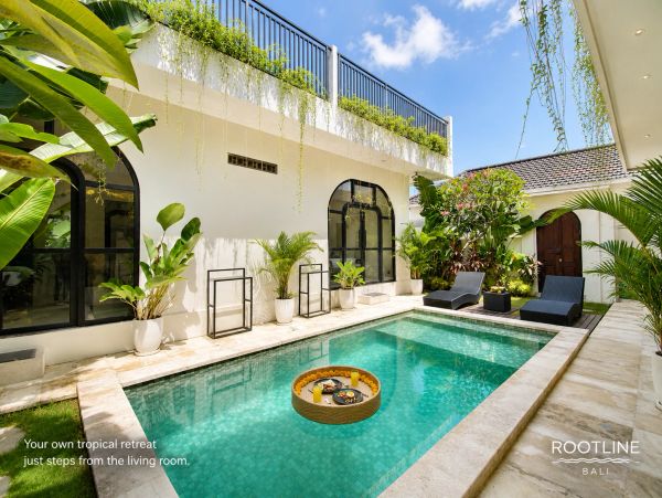 Tropical pool retreat with greenery and lounge chairs.