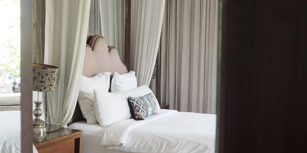 Elegant bedroom with white bedding and curtains.