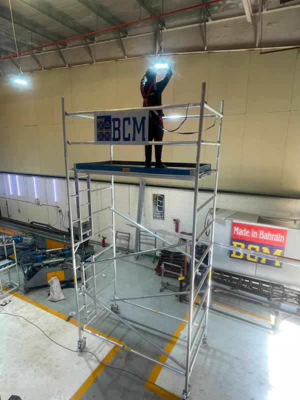 Worker welding on elevated scaffold inside industrial facility.