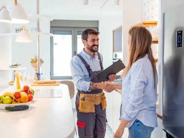 Technician shaking hands with a woman in a modern kitchen.