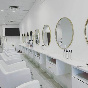 Beautiful, clean salon, white chairs, gold circle mirrors, sleek and chic!