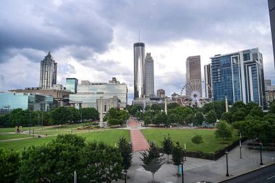 City skyline with a Ferris wheel and cloudy sky over a green park.