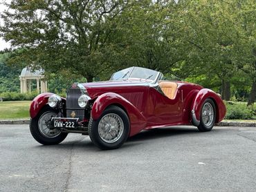 Classic red vintage convertible car parked outdoors.