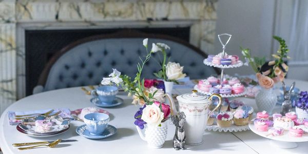 Elegant table set for a tea party with flowers and sweets.