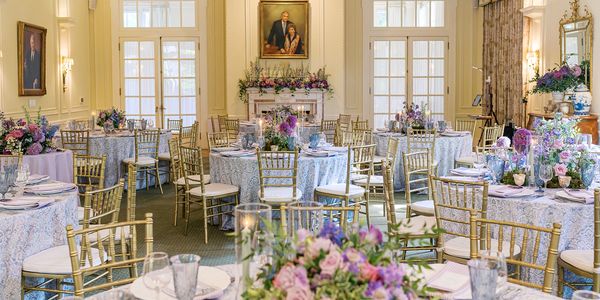 Elegant banquet hall with floral decorations and gold chairs.