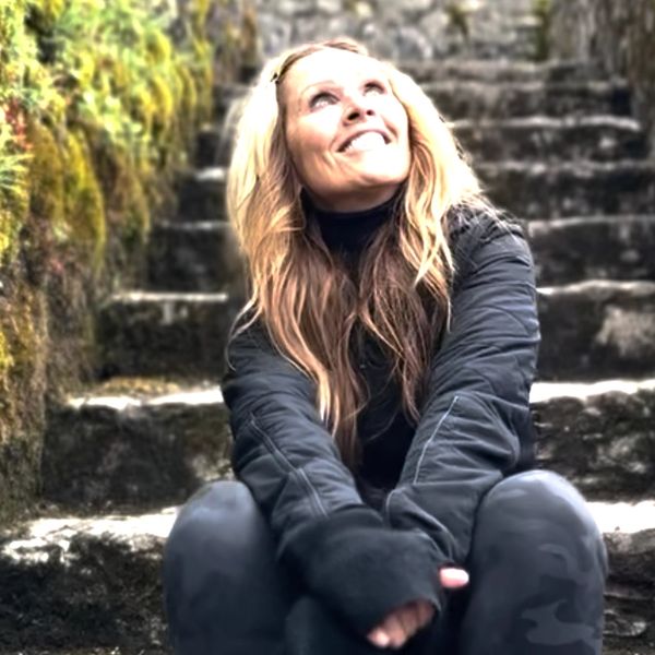 Annie sitting on a mountain stone staircase looking up smiling at the sky.