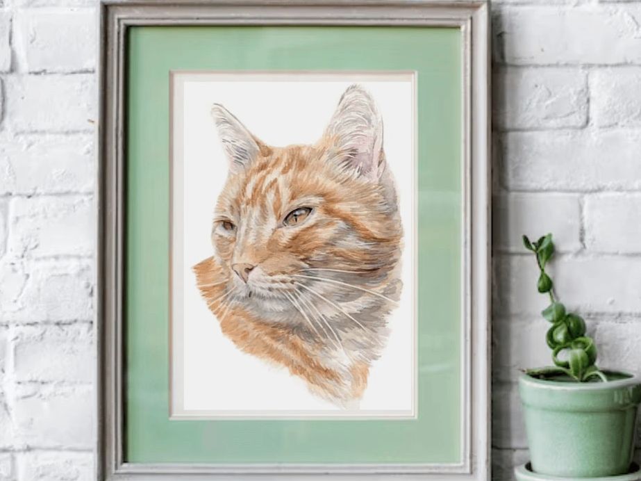 Hand-painted watercolour cat portrait by UK artist Jo Shepherd in a frame on white brick wall