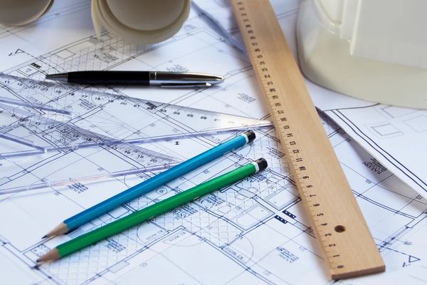 Architectural blueprints with pencils, ruler, and pen on a desk.