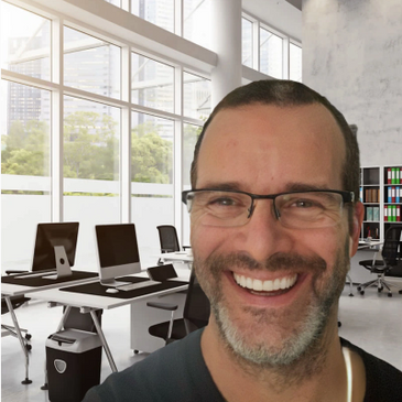 Smiling man with glasses in a modern office.